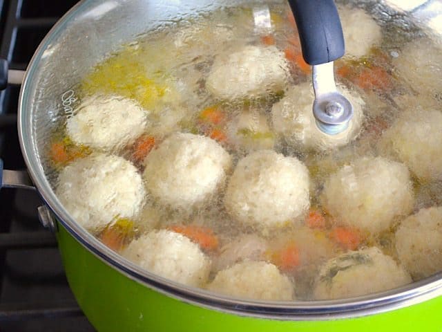 Simmering Matzo Balls in pot with veggies and broth 