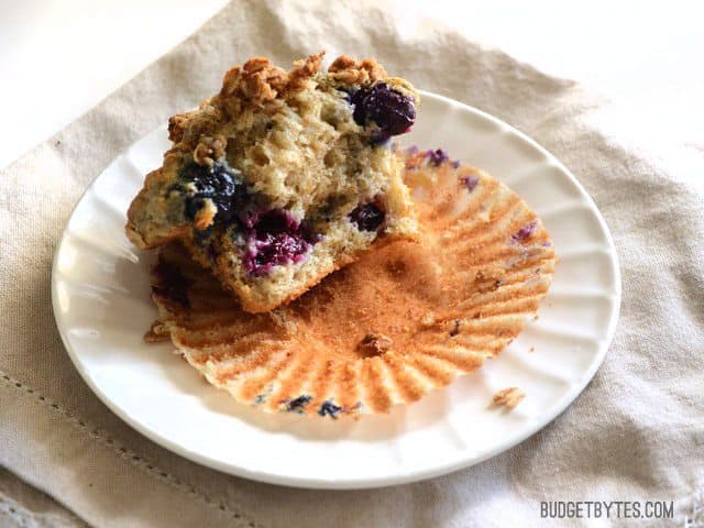 A half eaten Triple Berry Oatmeal Muffin on a plate