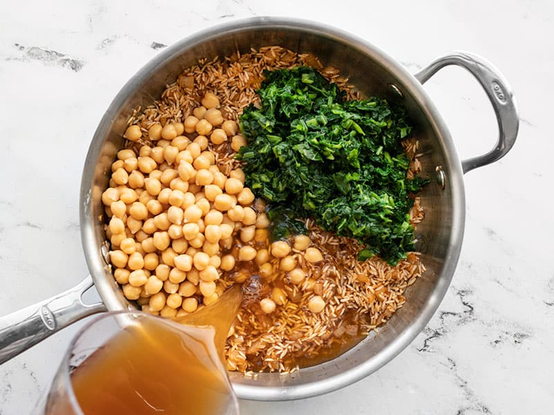 Chickpeas, spinach, broth, and lemon juice added to the skillet