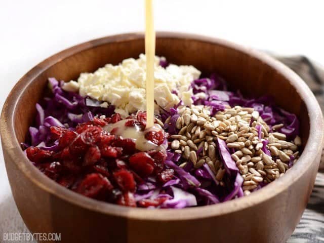 Champagne vinaigrette being poured over salad ingredients in the bowl