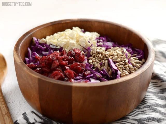 Cabbage, cranberries, feta, and sunflower seeds in a wooden bowl