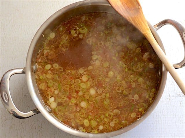 Hot and Sour soup broth in the soup pot, a wooden spoon sitting on the edge