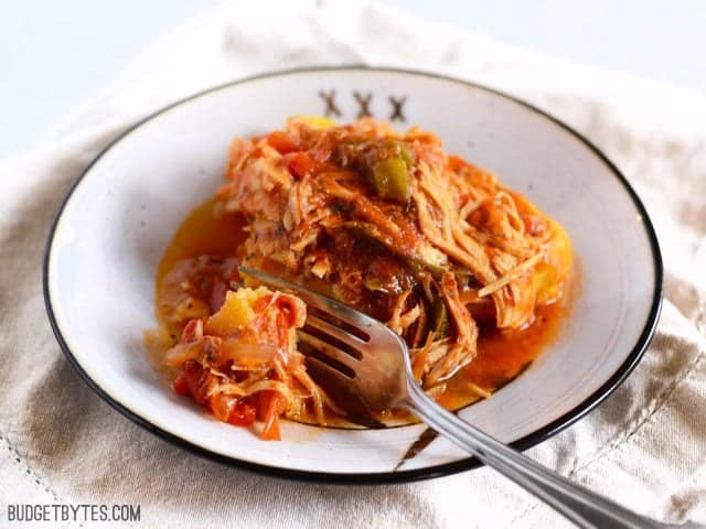 Slow Cooker Italian Chicken and Peppers on polenta with a fork taking a bite