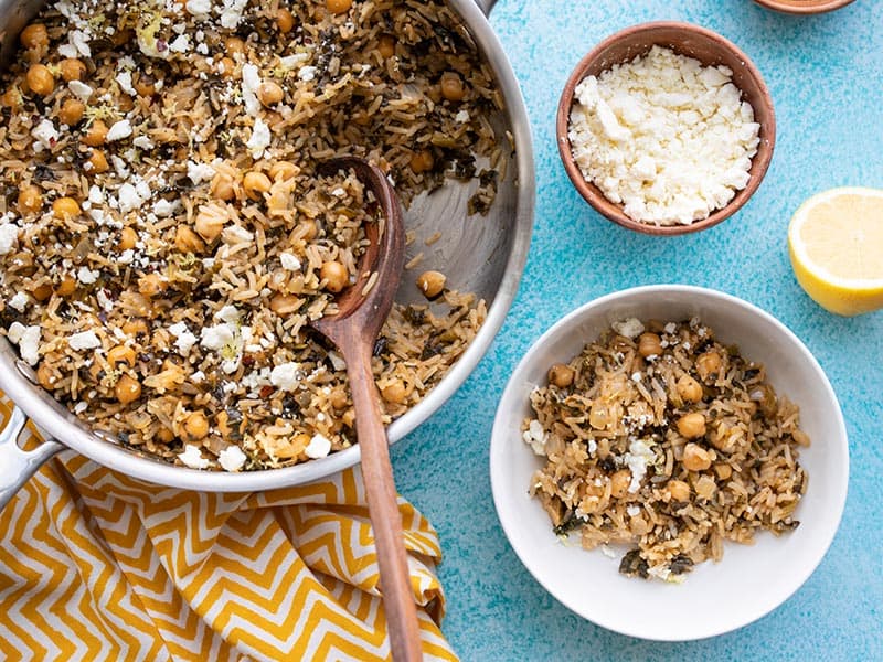 Spinach and Chickpea Rice Pilaf scooped out of the skillet and into a bowl. A small bowl of feta on the side.