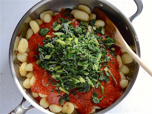 Sauce and frozen greens added to the skillet