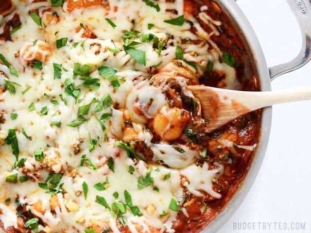 A skillet filled with cheesy gnocchi and herbs.