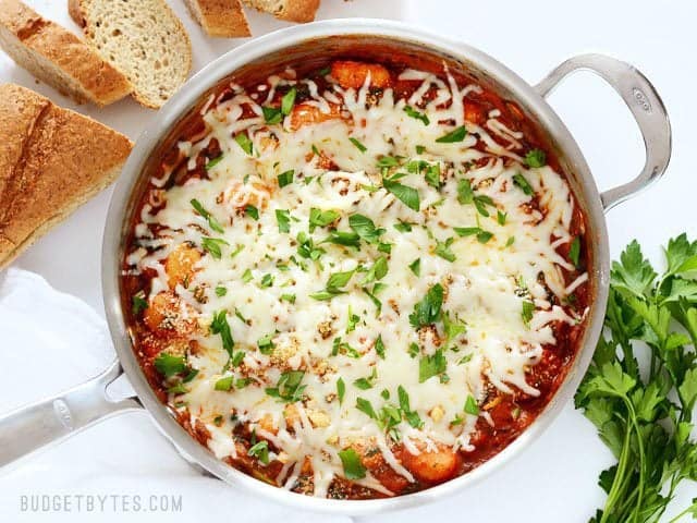 Overhead view of the finished Cheesy Gnocchi Skillet with bread and parsley on the side