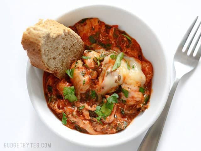 Overhead view of a bowl full of Cheesy Gnocchi with a slice of bread dunked in the side