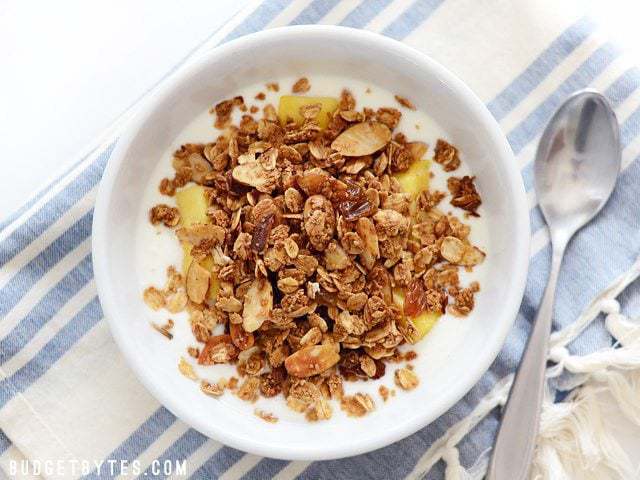 Overhead view of a bowl of Homemade Gingersnap Granola with yogurt, pineapple, and honey