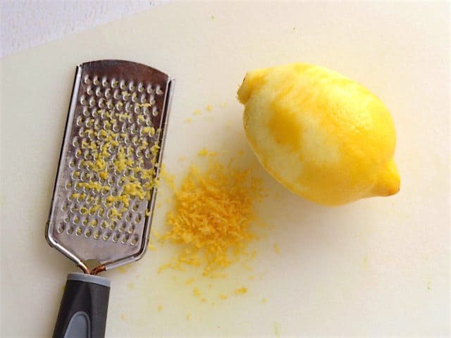 Zested lemon on a cutting board with a zester