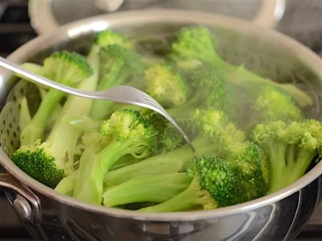 Steamed Broccoli being tested with a fork