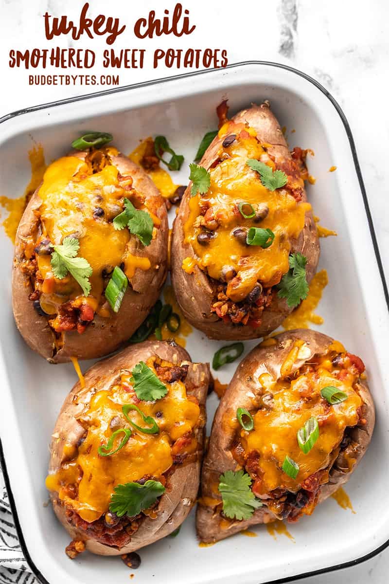 Overhead view of a baking dish with four turkey chili smothered sweet potatoes, title text at the top