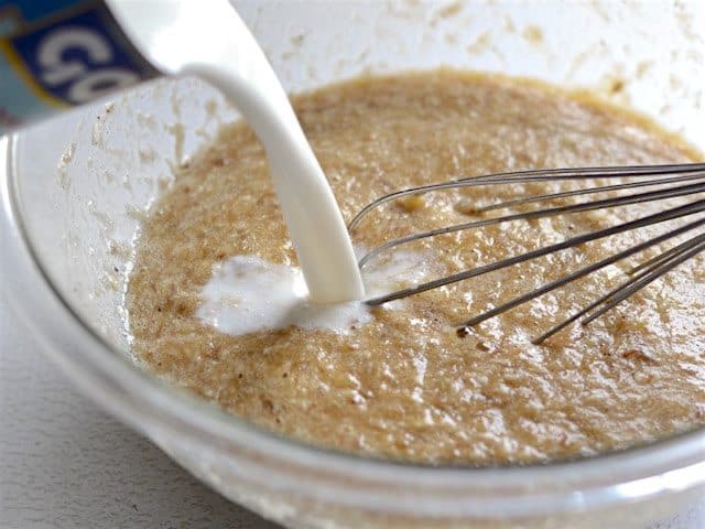 coconut milk being poured into the mixing bowl