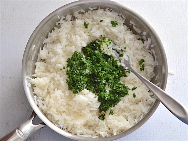 Lemon parsley mixture added to cooked rice in a sauce pot