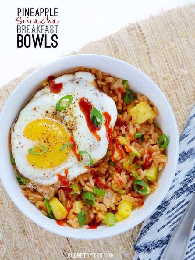 Overhead view of a Pineapple Sriracha Breakfast Bowl, drizzled with sriracha, and garnished with green onion.