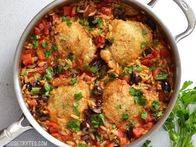 Skillet chicken with orzo and olives in a bowl.