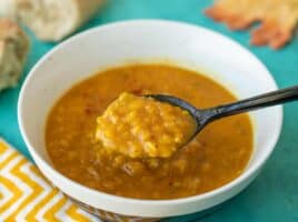 A spoonful of lentil and pumpkin soup being lifted from the bowl