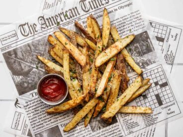 Overhead view of a pile of garlic parmesan fries with a small cup of ketchup