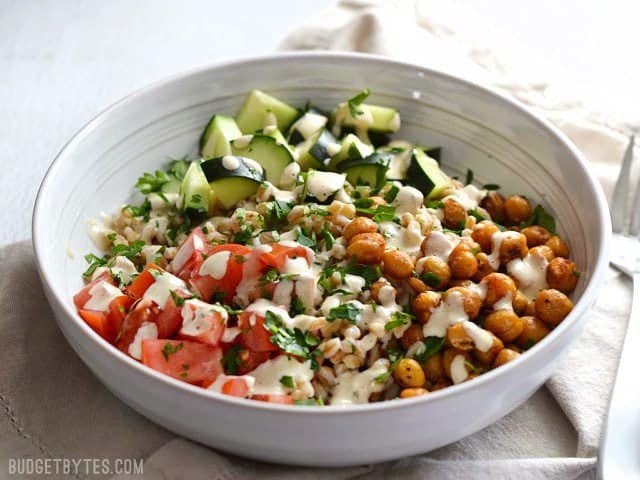 Front view of a bowl of Mediterranean Farro Salad  topped with tahini dressing and parsley