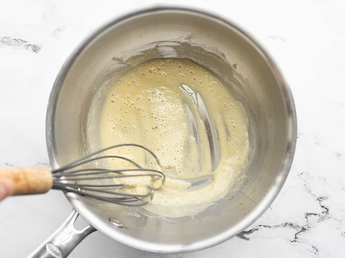 Butter and flour being whisked in a sauce pot