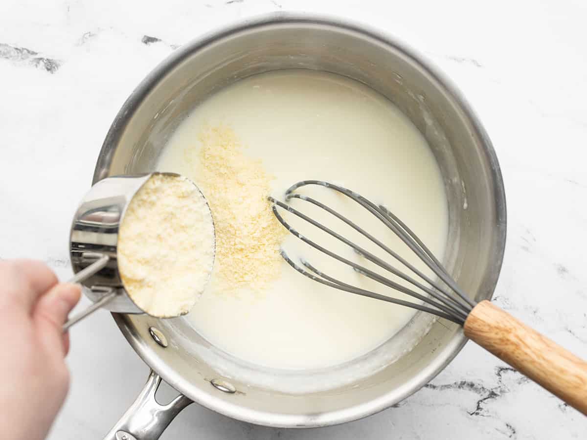 Grated Parmesan being added to the sauce pot