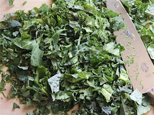 Chopped Kale on a cutting board with a chef's knife.