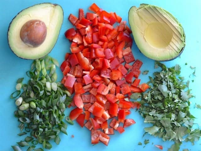 Chopped Vegetables (green onion, bell pepper, avocado, cilantro) on a blue cutting board