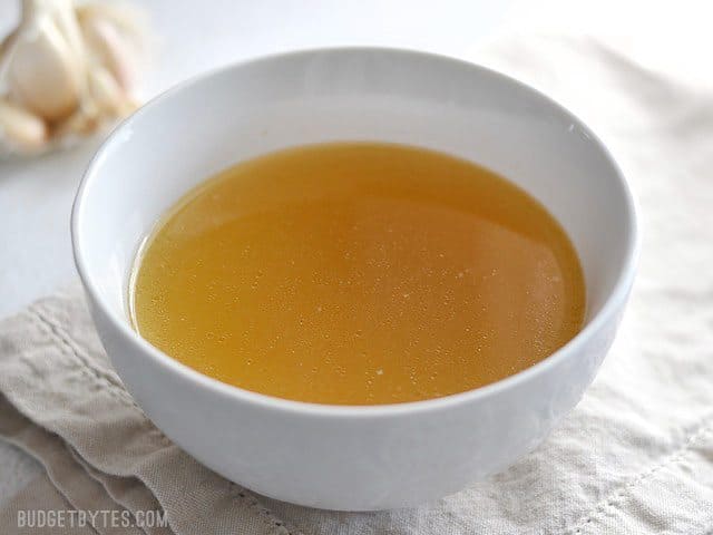 Instant pot chicken stock in a clear bowl.