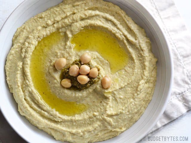 Close-up of creamy pesto hummus in a bowl.