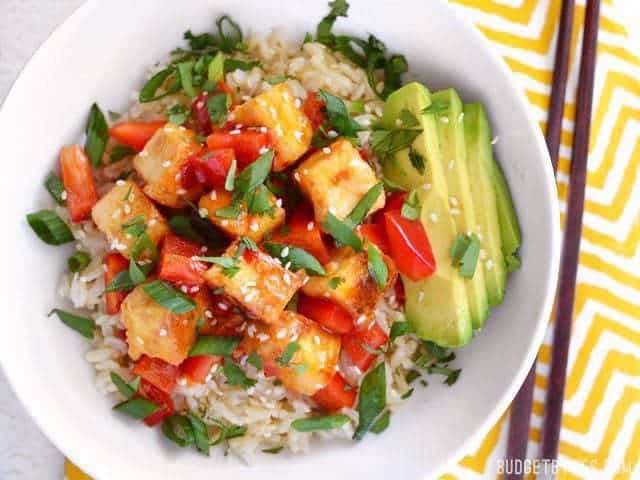 Close-up of sweet chili tofu bowls with toppings and chopsticks.