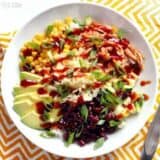 BBQ chicken burrito bowl with various toppings and a fork.