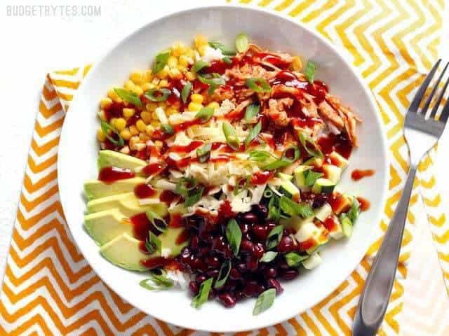 BBQ chicken burrito bowl with various toppings and a fork.