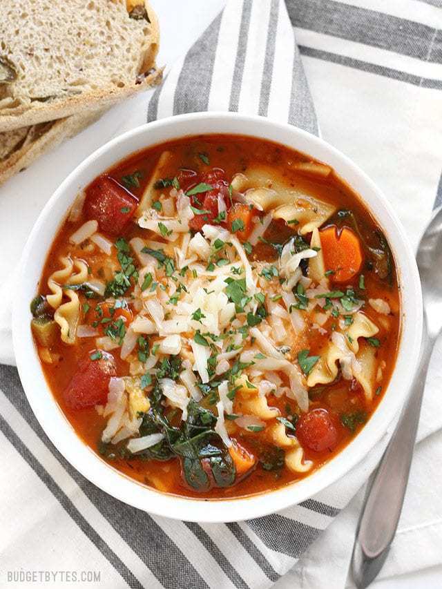 Overhead view of a bowl full of Garden Vegetable Lasagna Soup with crusty bread on the side