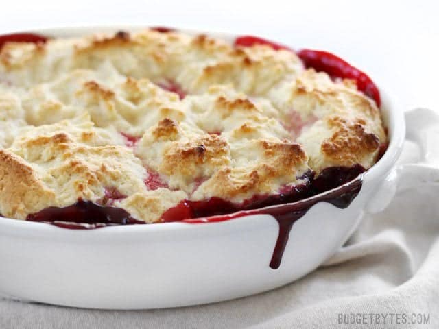 Side view of the baked Lemon Berry Cobbler with a bright berry juice drip down the side of the casserole dish