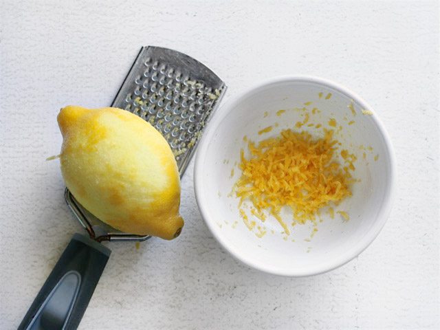 Lemon being zested into a small bowl