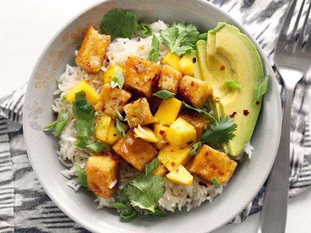 Close-up of mango coconut tofu bowl with toppings.