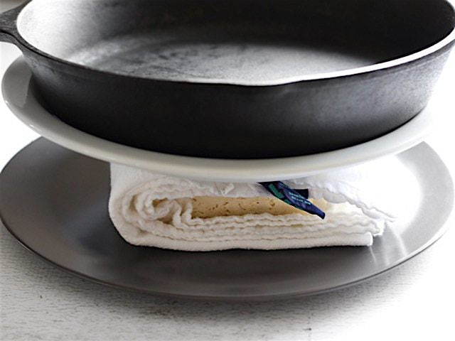 Pressing Tofu between two plates with a cast iron skillet used as the weight