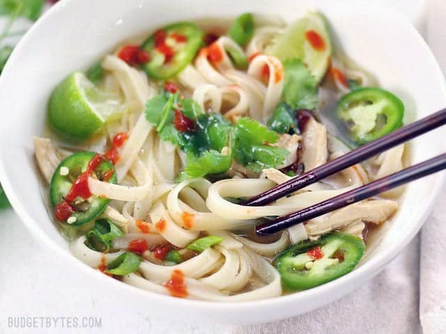 Front view of a bowl of Quickie Faux Phở with chopsticks picking up a noodle