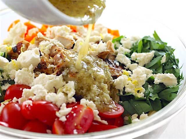 Dressing being poured over the ingredients in the bowl