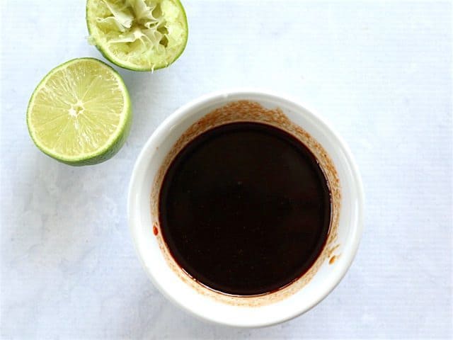 Dragon Noodle Sauce in a small bowl next to a cut lime