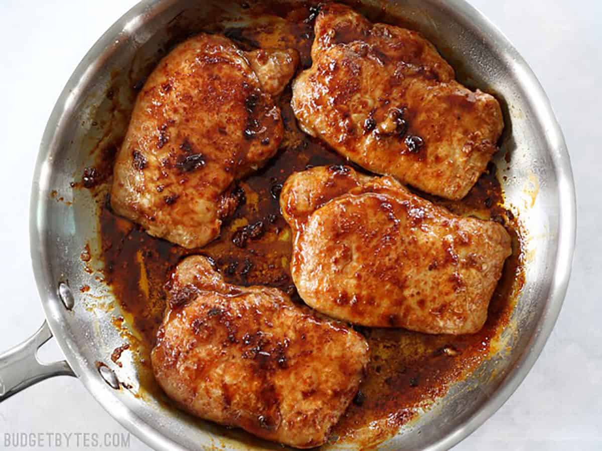 Overhead view of a skillet full of brown sugar glazed pork chops (no garnish).