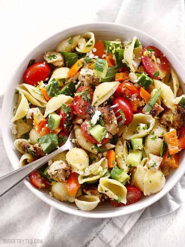 Close up overhead shot of Greek Chicken Pasta Salad in a bowl with a forkful laying in the middle.