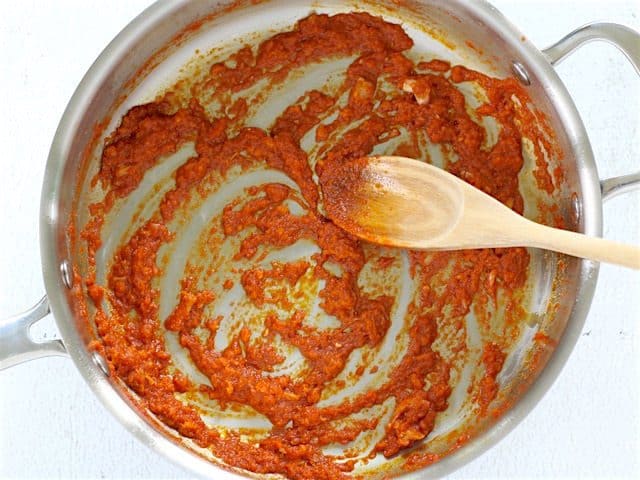 Sautéed Aromatics in the skillet with a wooden spoon