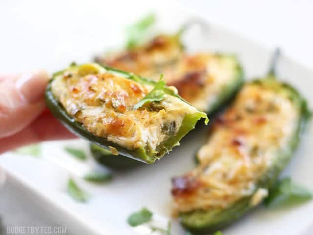 Close up of a cheesy stuffed jalapeño with a bite taken out.