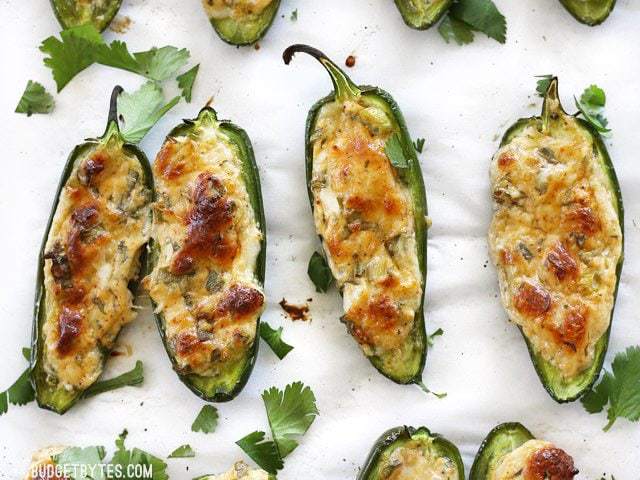 Baked cheesy stuffed jalapeños with browned cheese on top, garnished with cilantro