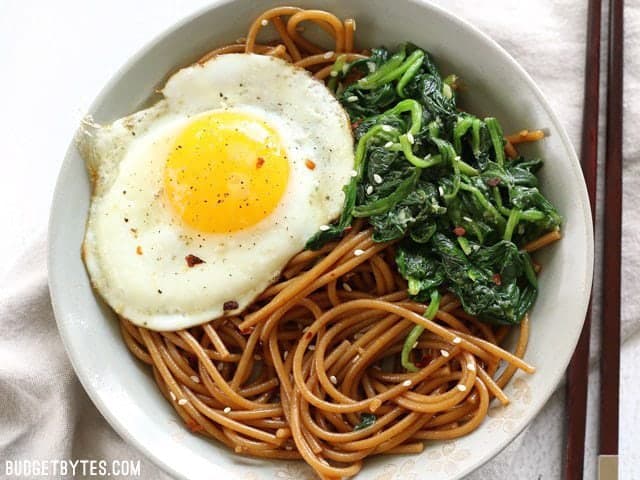 Close up overhead view of a bowl full of Sesame Noodles with Wilted Greens 