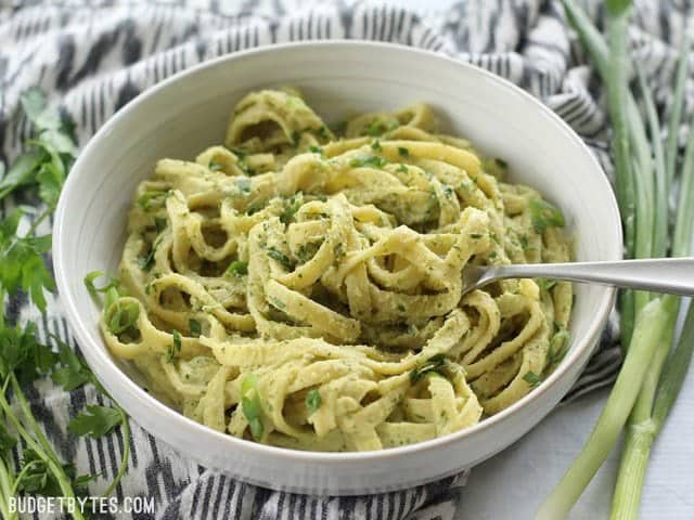 Front view of a bowl of Parsley Scallion Hummus Pasta with a fork twirled into the pasta