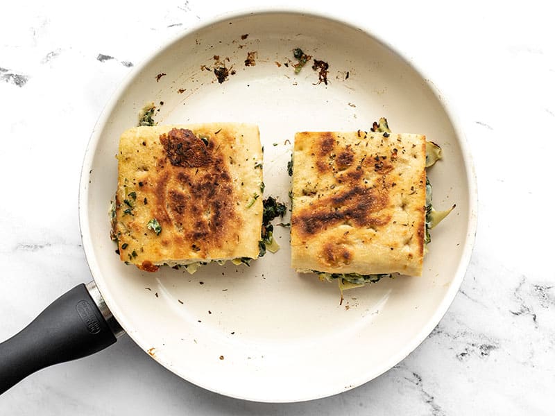 Spinach artichoke grilled cheese sandwiches being cooked in the skillet