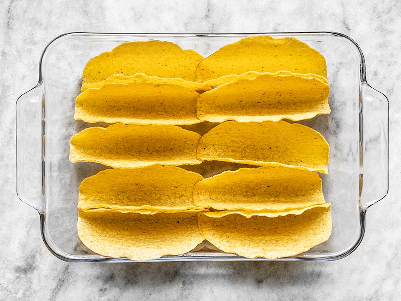 Empty taco shells arranged in a glass casserole dish