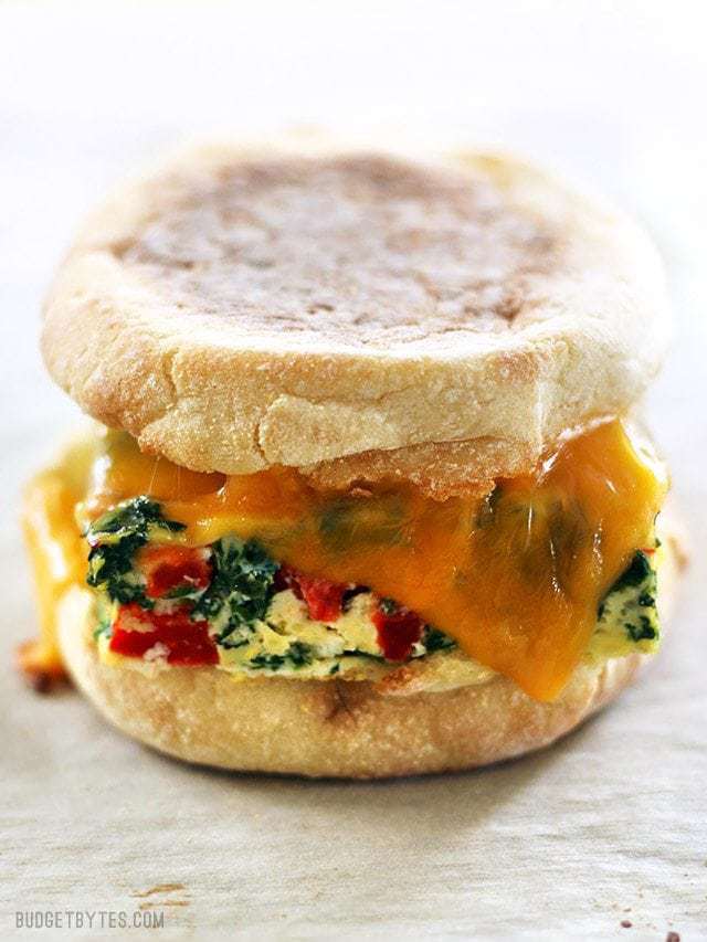 Close up side view of a Veggie Packed Freezer Breakfast Sandwich reheated with melted cheese.